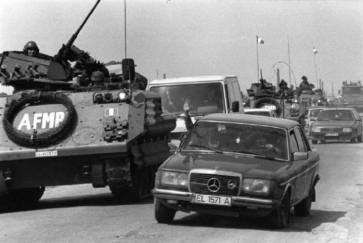 ALBANIA. A Mercedes overtakes a troop carrier, part of the multi-national force, on the road to Vlore. 1997.