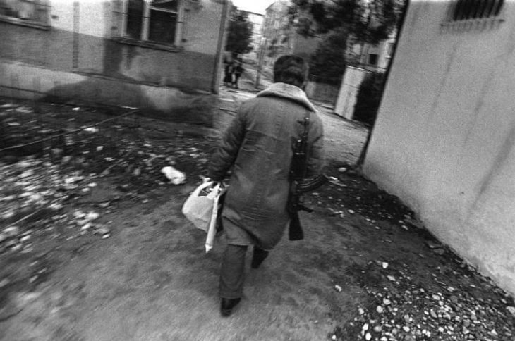 ALBANIA. Tirana. A shopper returns home with his Kalashnikov slung over his shoulder. 1997.